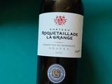 une bouteille de vin posée sur une table de billard, à côté d'une queue de billard