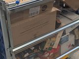 a cart full of boxes on the street with a blue car in the background