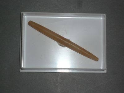 un stylo en bois posé sur un plateau blanc, sur une table