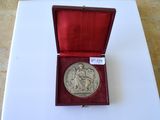 une vieille médaille d'argent dans un écrin rouge posé sur une surface blanche