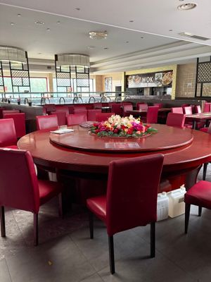 de nombreuses chaises rouges disposées autour d'une table ronde dans un restaurant