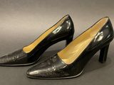 a pair of black high heeled shoes on a gray surface