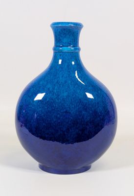 un vase bleu posé sur une surface blanche