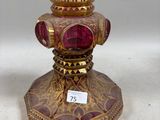 un vase doré et rouge surmonté d'un verre rouge