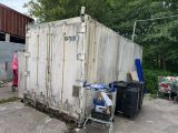 une photo représentant un conteneur maritime devant lequel se trouve un caddie