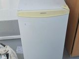 a small white refrigerator next to a bag of food on the floor