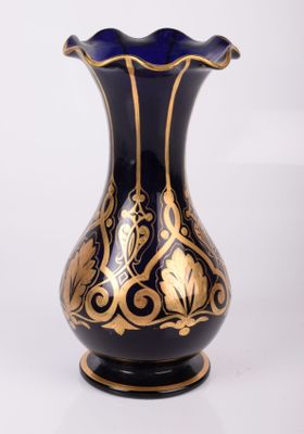 un vase bleu et or posé sur une surface blanche