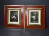 deux tableaux encadrés représentant des fleurs, posés sur une table dans une pièce