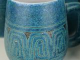 a blue mug sitting on a table next to other blue mugs