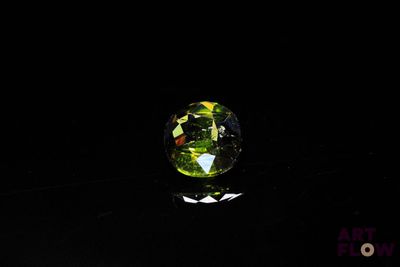 a close up of a green glass ball on a black surface