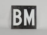une vieille enseigne en noir et blanc sur laquelle figurent les lettres « bm »