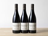 trois bouteilles de vin posées sur une table en bois