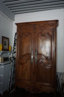 une grande armoire en bois placée dans un coin d'une pièce où se trouve un radiateur