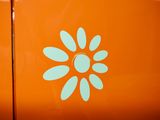 an orange refrigerator with a flower sticker on it