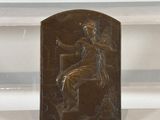 a bronze plaque of a woman sitting on a chair