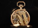 a close up of a gold pocket watch on a black surface