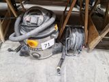 un aspirateur et un tuyau posés par terre dans un garage