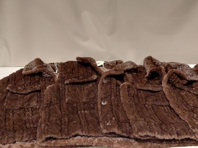 un gilet en fourrure marron posé sur une table blanche