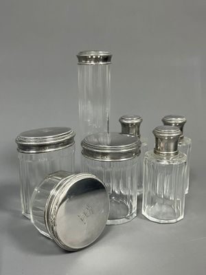 quatre bocaux en verre avec des couvercles argentés, posés sur une surface grise