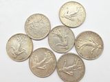 six different british coins sitting on top of each other on a white surface