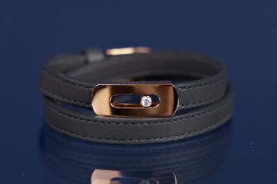 bracelet en cuir noir avec un fermoir plaqué or sur fond bleu