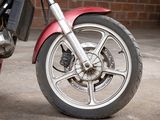 a red motorcycle parked in a parking lot with a brick wall in the background