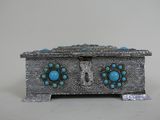 une boîte en argent ornée de pierres turquoise, posée sur une table