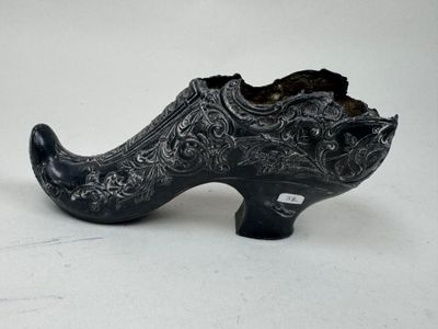 une chaussure noire posée sur une surface blanche