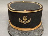 un chapeau noir orné d'une bordure dorée et d'un écusson
