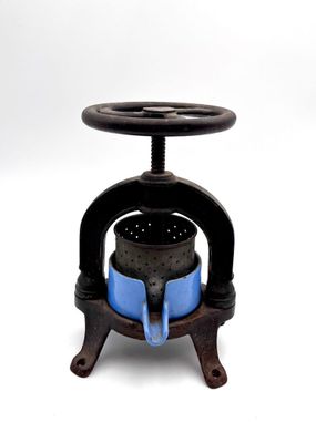Presse à vis en métal avec récipient en céramique bleu.