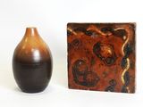 two vases sitting next to each other on a white surface