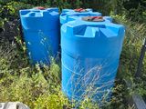 two blue barrels sitting next to each other in the grass