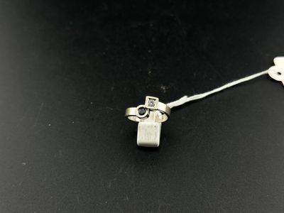 un gros plan d'une petite croix en argent sur une surface noire