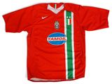 un gros plan sur un maillot de foot rouge orné d'une bande verte et blanche