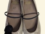 pair of silver shoes with a black pom pom on the toe