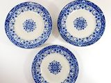 three blue and white plates with floral designs on them