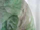 a close up of a green marble sculpture on a white surface