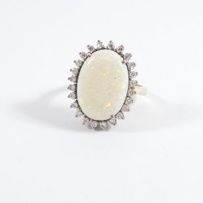 an oval oplite and diamond ring on a white background