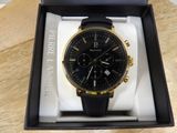 the black and gold watch is in the box on the table