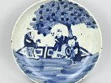 a blue and white plate with a picture of a man and a woman on a boat