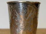 a silver cup with a design on it on a wooden table