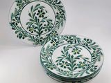 two green and white plates with flowers on them on a white surface