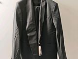 une veste noire suspendue à un cintre sur un mur blanc