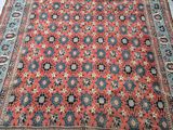 a red and blue rug on a floor next to a chair