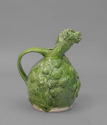 un vase vert surmonté d'une tête de dragon
