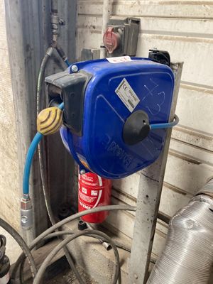 a blue tank with a hose attached to it next to a wall