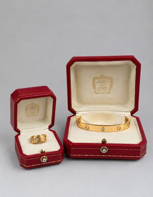 two red leather jewelry boxes with gold rings inside of them