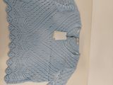 un pull bleu en tricot dans une boîte posée par terre