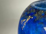 a blue vase with gold writing on it sitting on a table