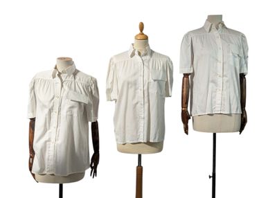 trois mannequins vêtus de chemises blanches, exposés sur un présentoir en bois